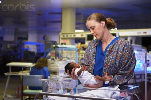 Enfermeira segurando prematuro na UTI Neonatal